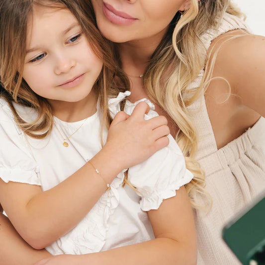 14k gold baby bracelet worn by young girl, showcasing elegance with cultured freshwater pearls.