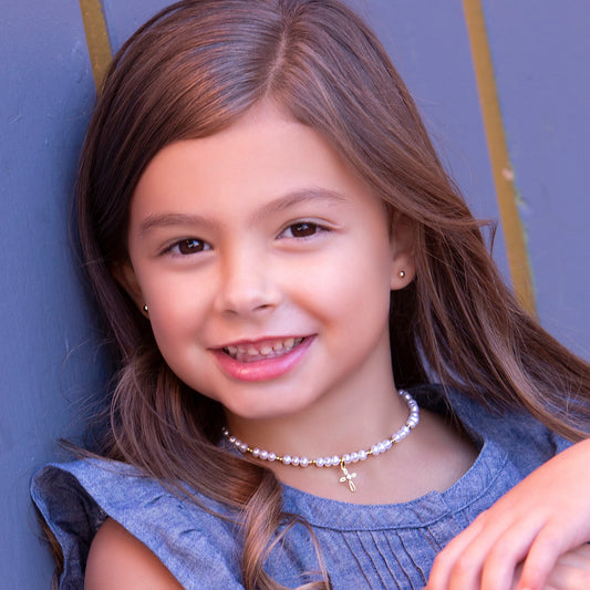 Young girl with a pearl necklace against a blue wall
