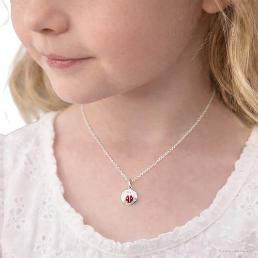 Child's neck wearing children's necklaces with a sterling silver ladybug medallion pendant.