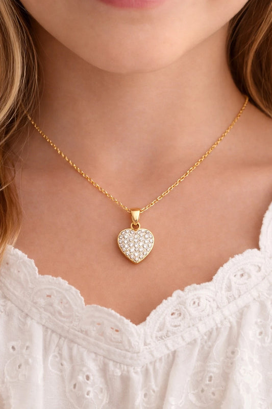 Children's pendants in solid 9k gold with white CZ heart design worn by a girl.