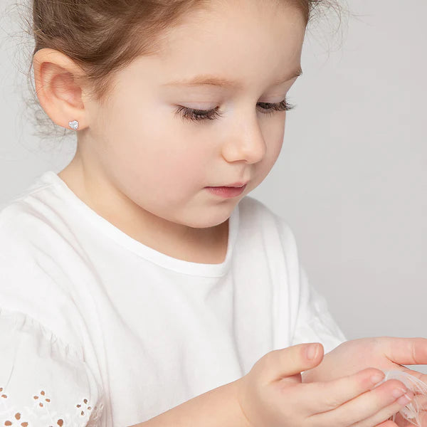 Young girl wearing a white shirt with a subtle pattern on a light gray background