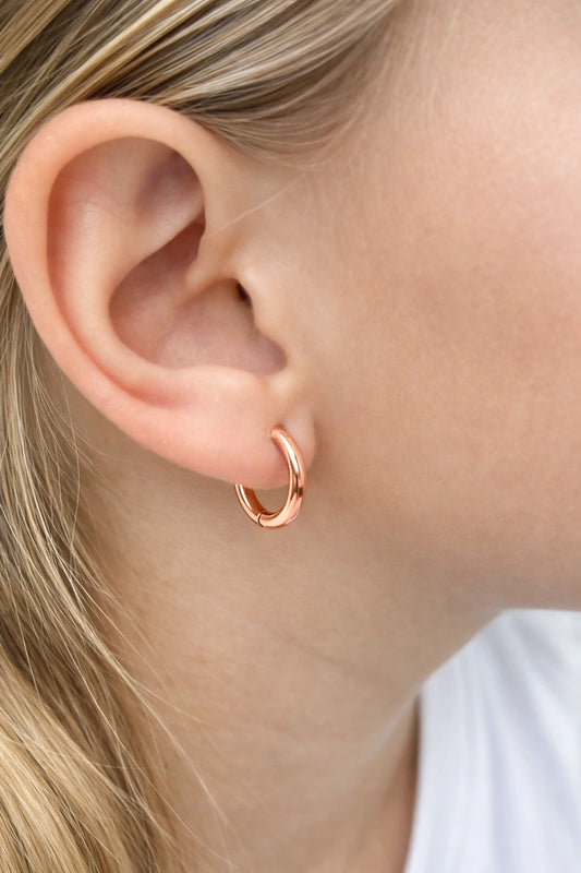 Children's earrings in 18k rose gold plated hoop style worn by a child, showcasing a polished finish.