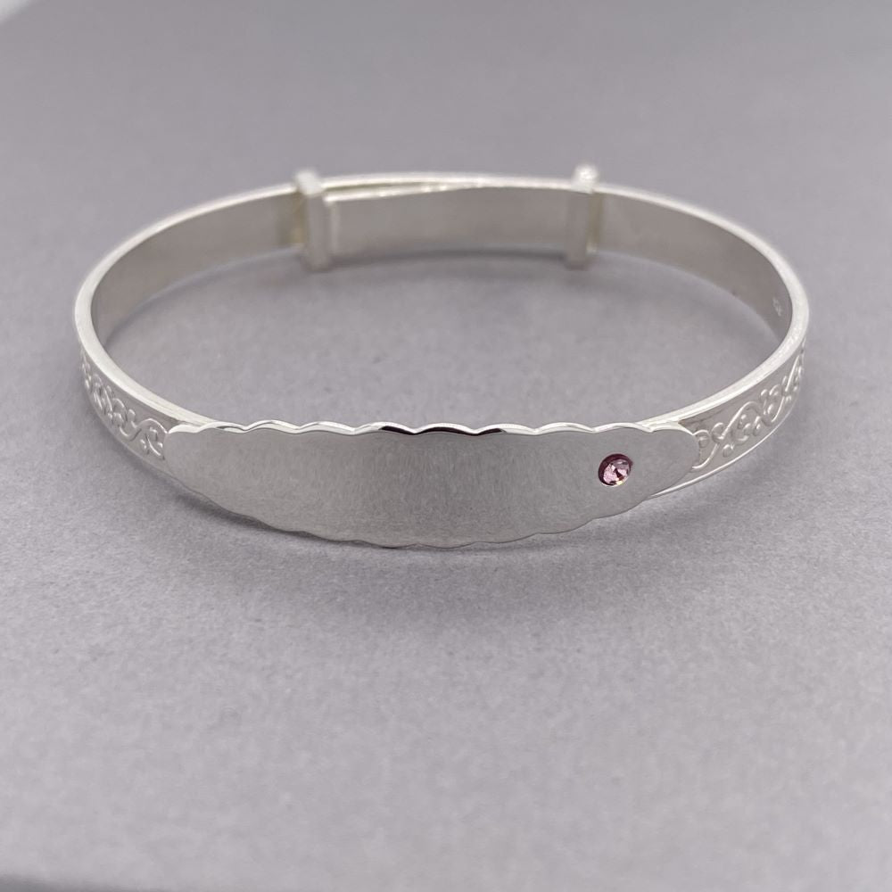 Silver expanding baby bracelet with embossing and name plate featuring a single pink cz stone