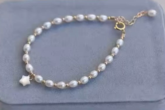 Pearl bracelet - 14k gold plated freshwater pearl with shell star centerpiece on a blue velvet surface.