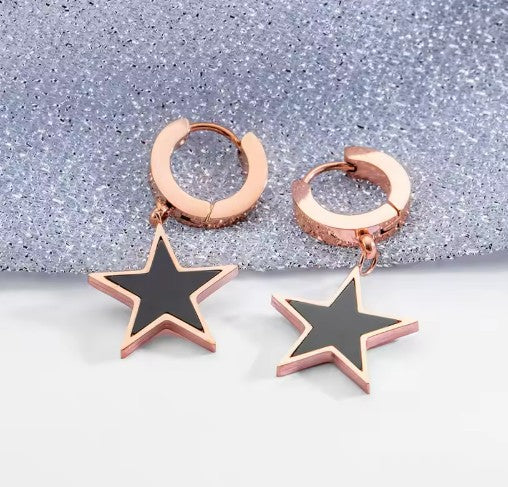 rose gold huggie earrings for teens and mothers featuring black star accents on a glittery background.