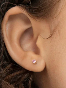 A close-up of an ear with a pink cubic zirconia titanium earring, showcasing the titanium earrings' elegance.