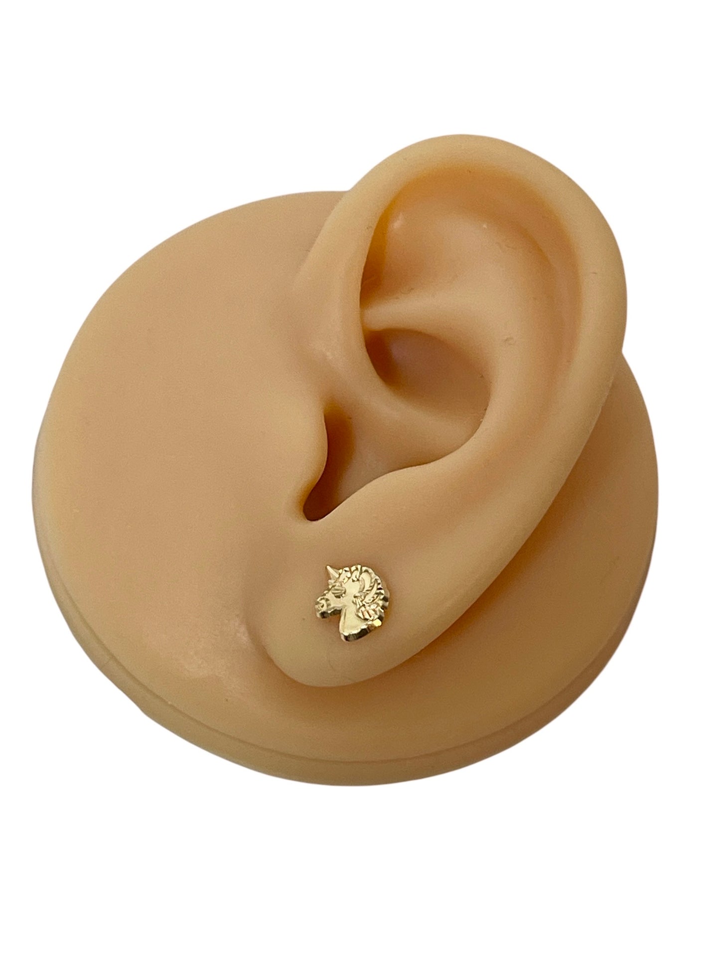 Unicorn earrings displayed on a model ear with 14k solid gold unicorn stud design.