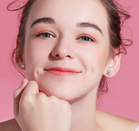 a young teen girl with aurora borealis cubic zirconia studs in her ears against a pink studio background