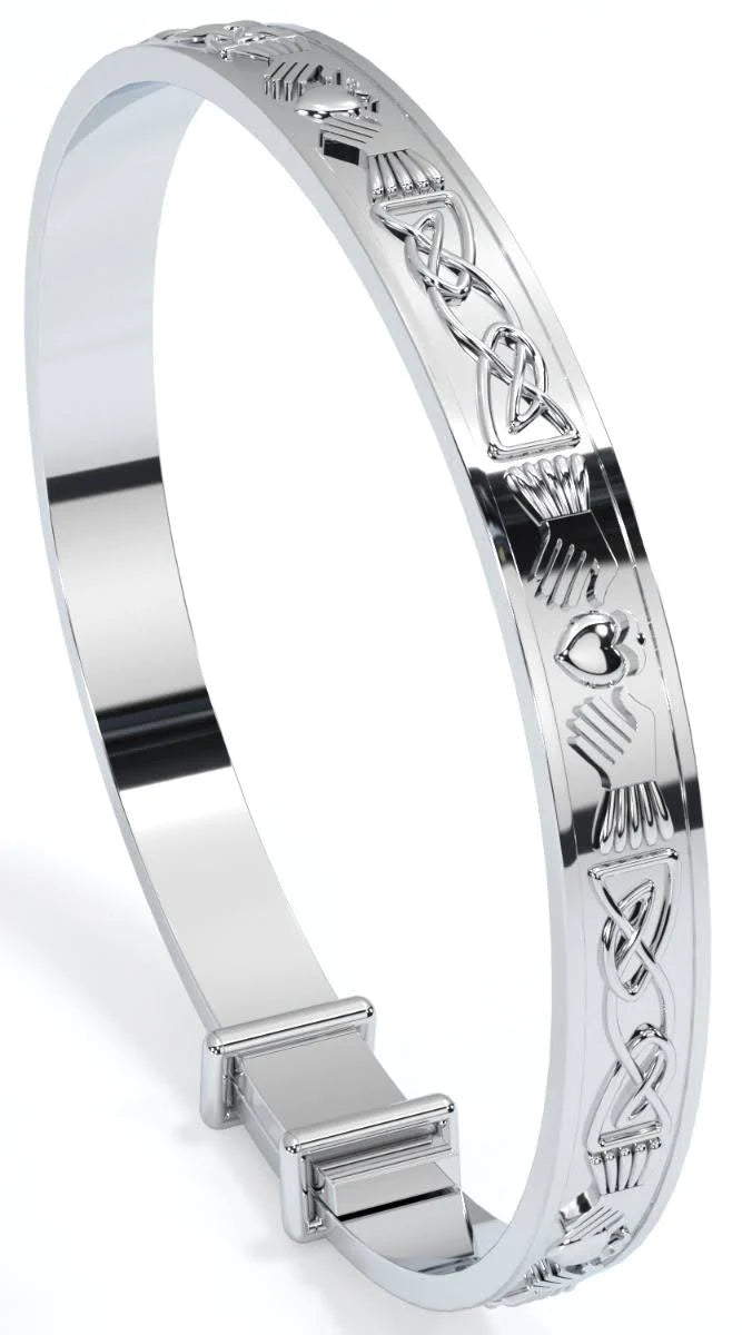Sterling silver expandable baby bangle engraved all around with Claddagh heart, hands, and crown motifs in a continuous Celtic knot pattern, shown on a white background standing on its side