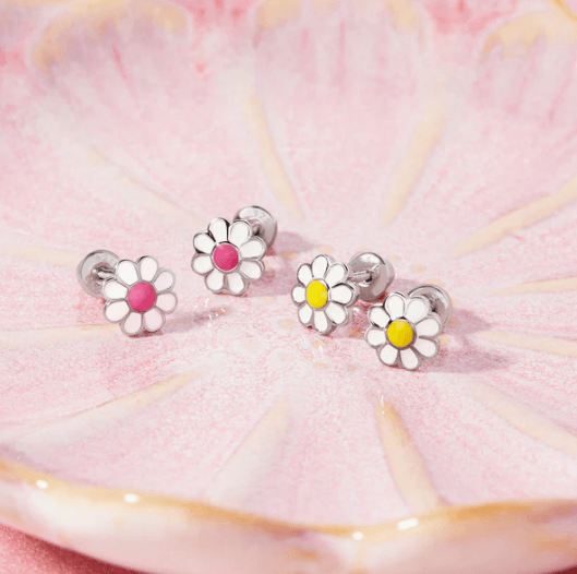 Set of four daisy-shaped earrings with colored centers on a pink and yellow background