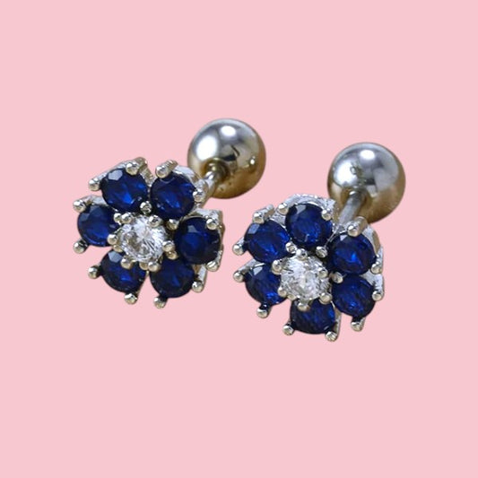 Pair of earrings with blue gemstones and clear center on a pink background