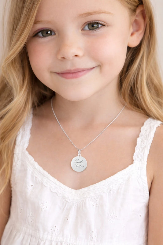 Child wearing a sterling silver Little Sister pendant necklace, showcasing children's necklaces for siblings.