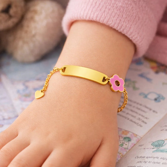 Children's identity bracelet with a gold plated charm and pink flower, displayed on a child's wrist.