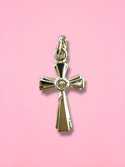 Gold cross pendant with a diamond on a pink background