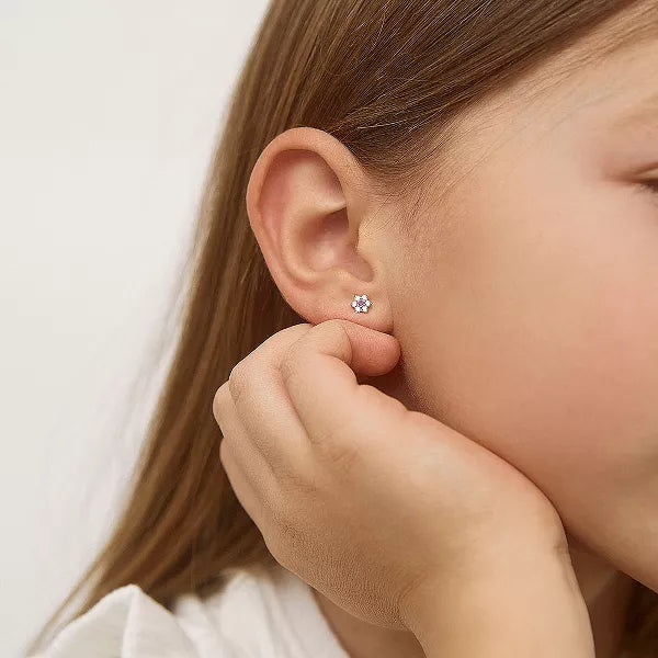 Close up of a girl's ear with sterling silver flower studs with white and pink cubic zirconia in her lobe