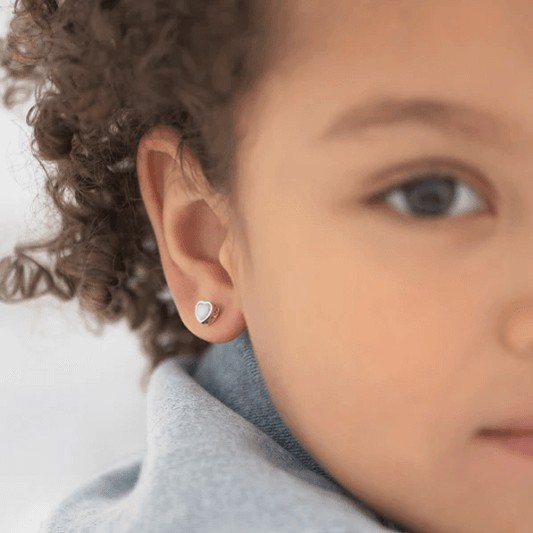 Close-up of a child wearing a heart-shaped earring with a neutral background