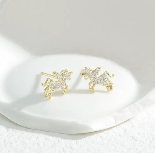 Gold pegasus unicorn-shaped earrings on a white dish