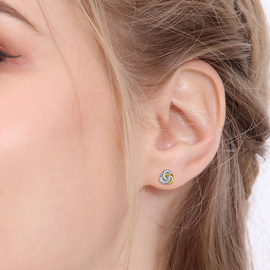 Endless knot earrings worn in a model's ear, showcasing 925 sterling silver and gold plating with cubic zirconia.