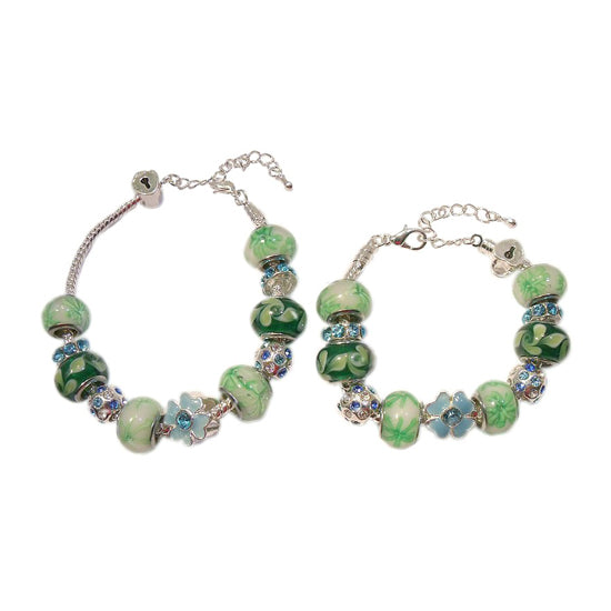 A pair of European style baby/children's bracelets with a mix of blue, green, and white lampwork beads, silver plated spacers, and heart-shaped locket charms.
