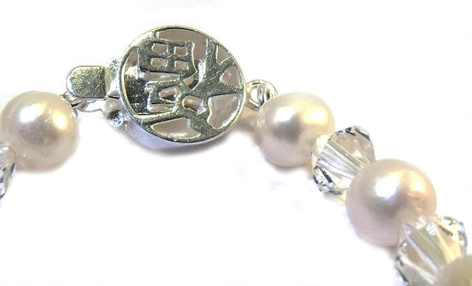 Close-up of a baby bracelet featuring creamy white freshwater pearls and Swarovski crystals with a sterling silver clasp.