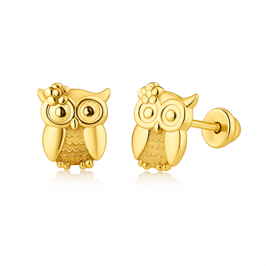 A pair of polished gold owl-shaped stud earrings on a white background; one earring faces forward showing its detailed round eyes, textured wings, and a small flower accent, while the other is turned to reveal its post and screw back