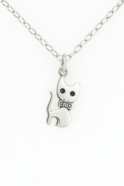 Product image of a silver cat pendant necklace with a stylized design, featuring indented black eyes and a bowtie detail. The pendant hangs from a silver chain with oval links, displayed against a plain white background.