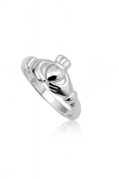 Close-up of a sterling silver Claddagh ring on a white background with a subtle reflection; the design features two hands holding a heart topped by a crown.