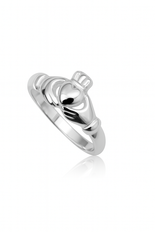 Close-up of a sterling silver Claddagh ring on a white background with a subtle reflection; the design features two hands holding a heart topped by a crown.