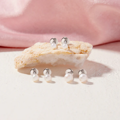Baby pearl earrings with 3mm white simulated pearls and sterling silver safety screw backs, displayed on a textured surface.