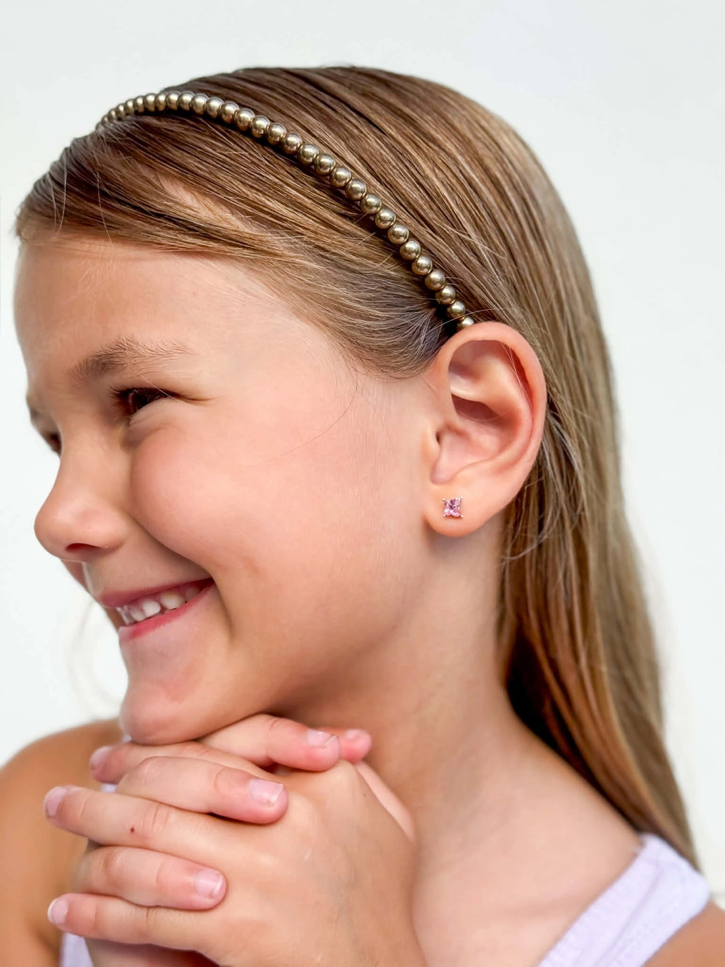A girl wearing children's earrings featuring pink Austrian crystal butterfly studs and a stylish headband.