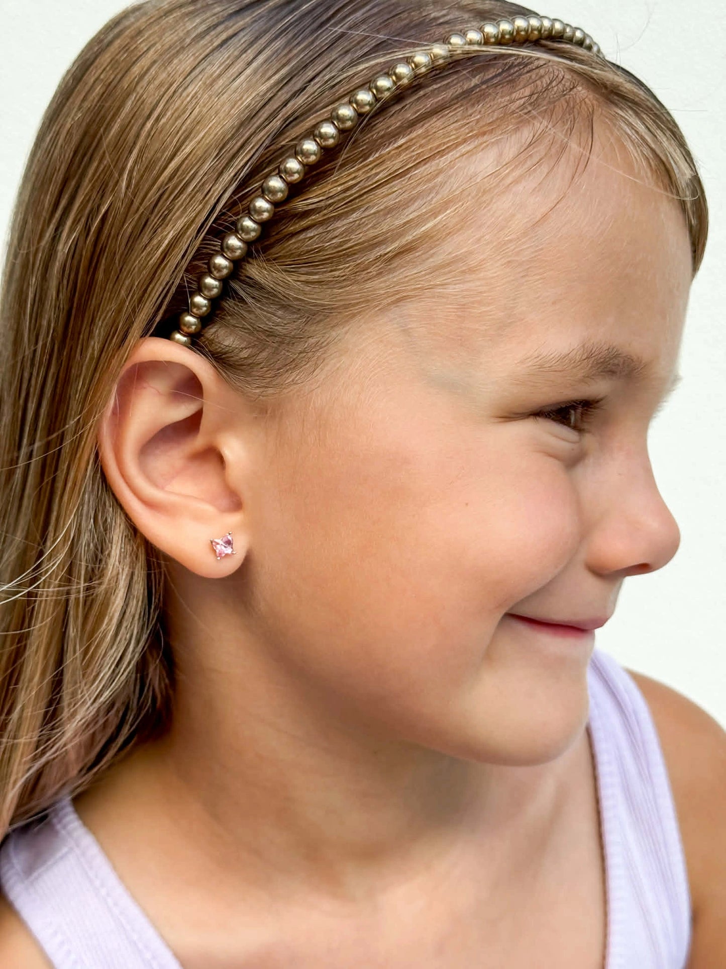 Children's earrings - 925 sterling silver pink Austrian crystal butterfly studs worn by a smiling girl.