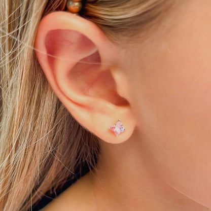 Close-up of a girl's ear wearing children's earrings with pink Austrian crystal butterfly studs.