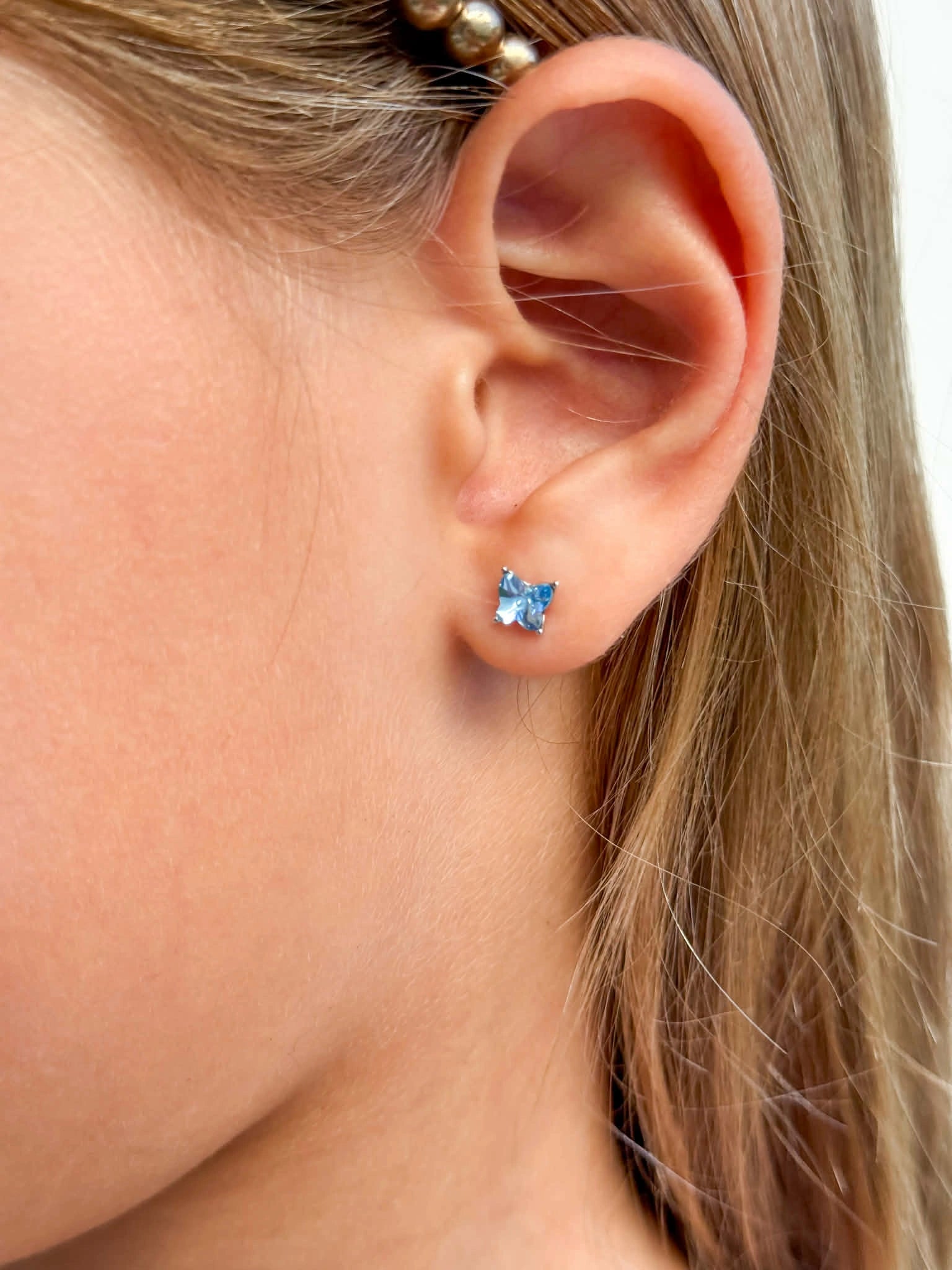 Children's earrings featuring blue Austrian crystal butterfly studs on a child's ear.