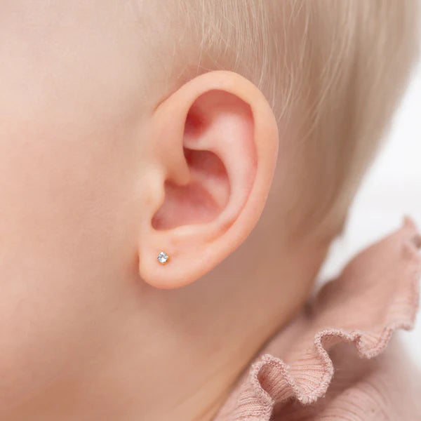 CZ stud earrings worn by a child, showcasing a small sparkling cubic zirconia in a classic setting.