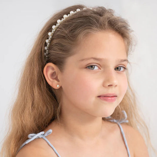 Girl wearing pearl headband and CZ stud earrings, showcasing a bright smile and a stylish look.