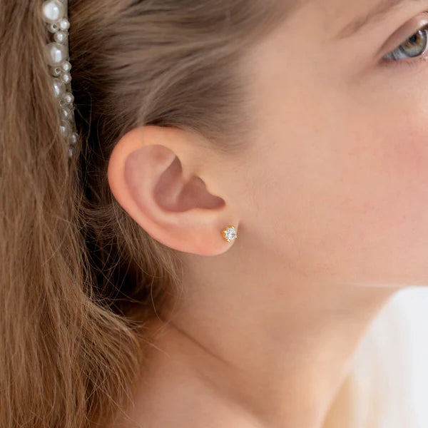 CZ stud earrings worn by a girl, showcasing 5mm clear cubic zirconia in classic gold settings.