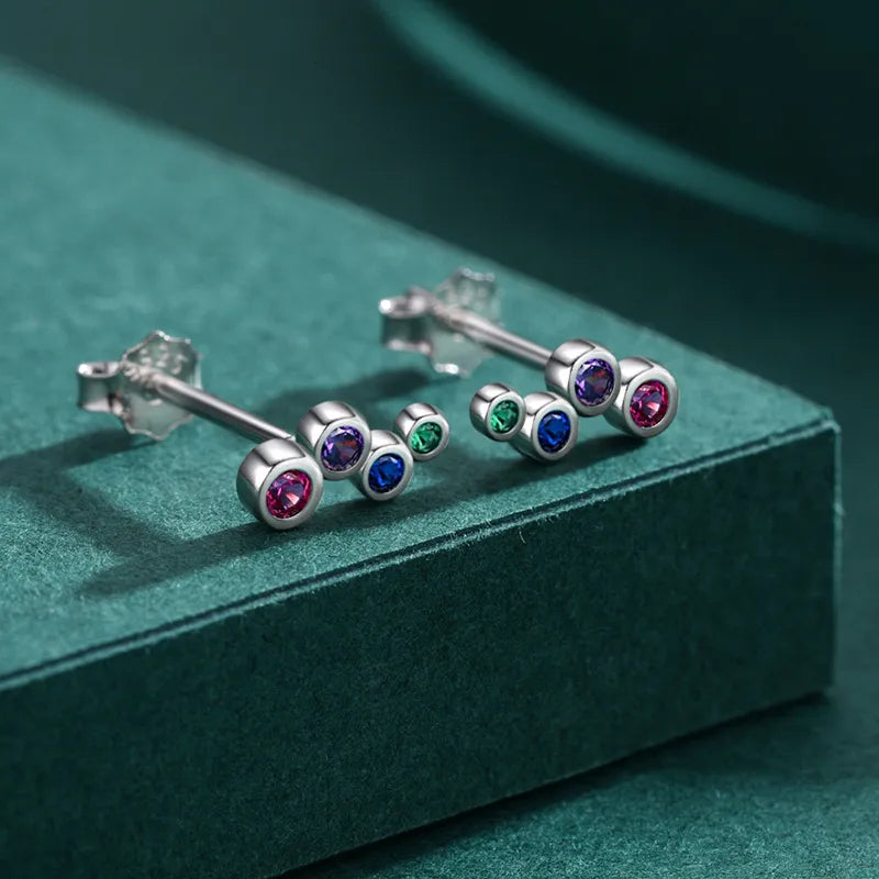 CZ stud earrings in sterling silver with multiple bezel set coloured CZ stones on a green background.