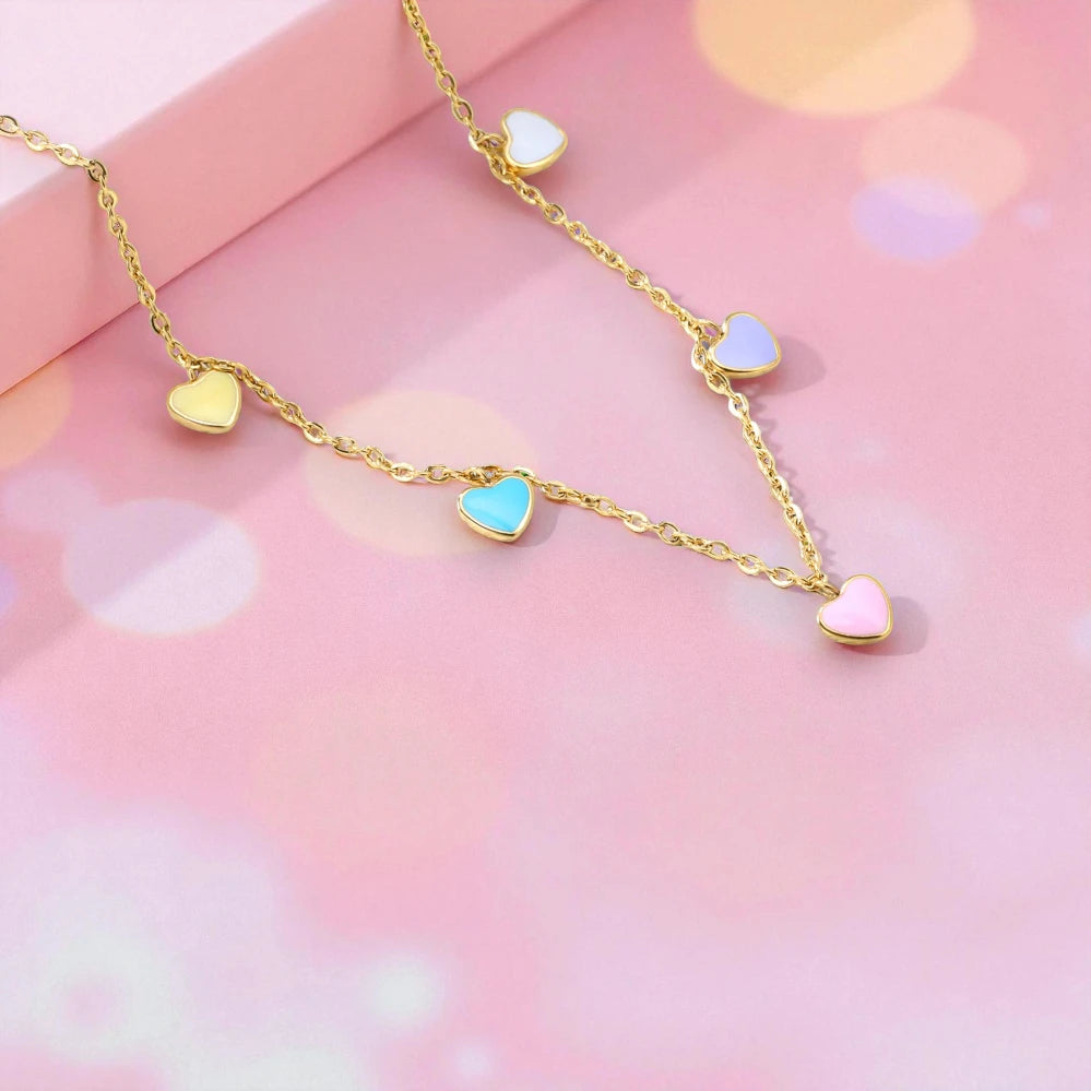 Candy heart necklace featuring 18k gold plated enamel heart charms on a pink background.