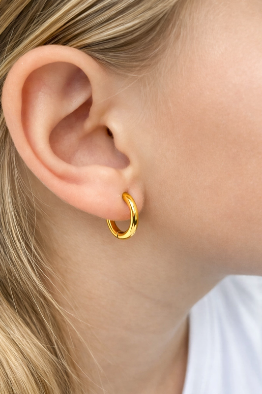 Children's earrings featuring 18k gold plated hoop design on a young girl's ear.