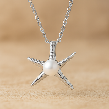 Sterling silver starfish pendant necklace with a centred pearl, displayed on a soft, sandy lifestyle background.