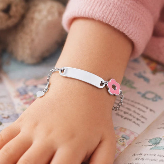 Children's identity bracelet with pink enamel flower charm on a child's wrist.
