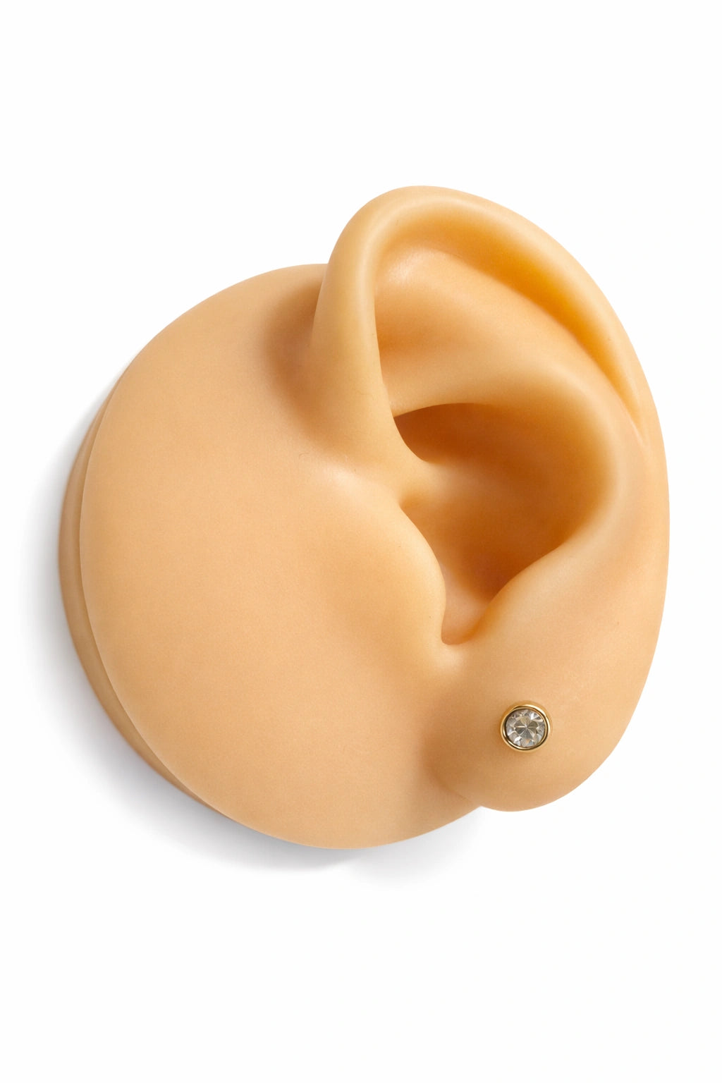 Children's earrings displayed on a realistic ear model featuring a screw back stud with cubic zirconia in gold setting.