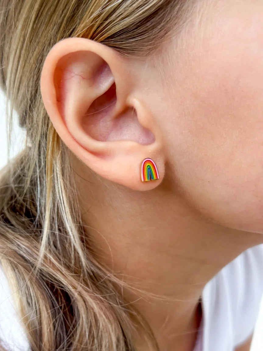 Children's earrings featuring a colorful rainbow stud close-up on a girl's ear.