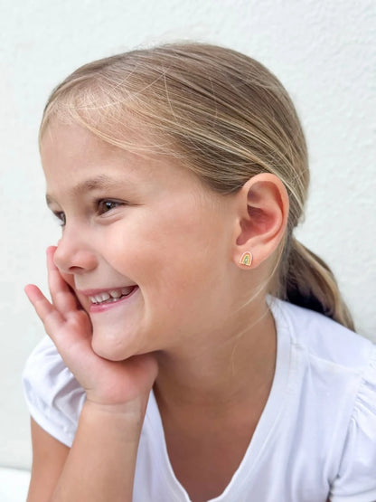 Child's smiling face showcasing colorful children's earrings in the shape of a rainbow.