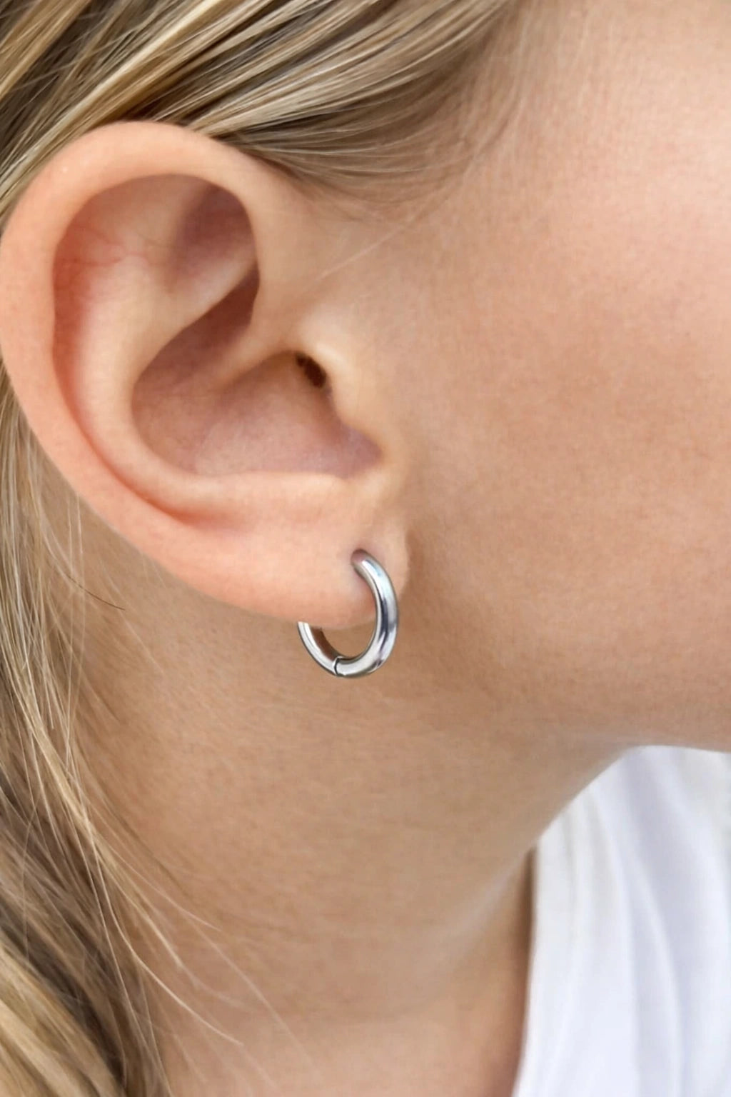 Close-up of a child's ear adorned with 316L surgical steel hoop earrings, showcasing a polished 10mm design for children's earrings.
