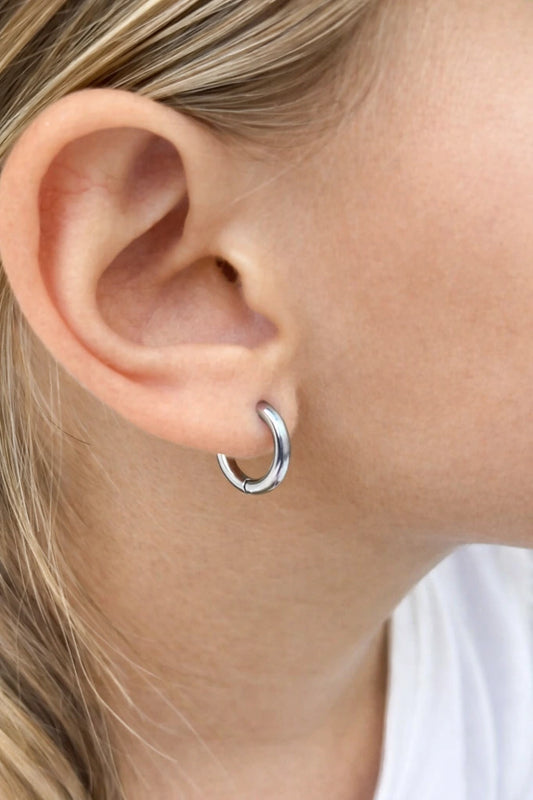 Close-up of a child's ear adorned with 316L surgical steel hoop earrings, showcasing a polished 10mm design for children's earrings.