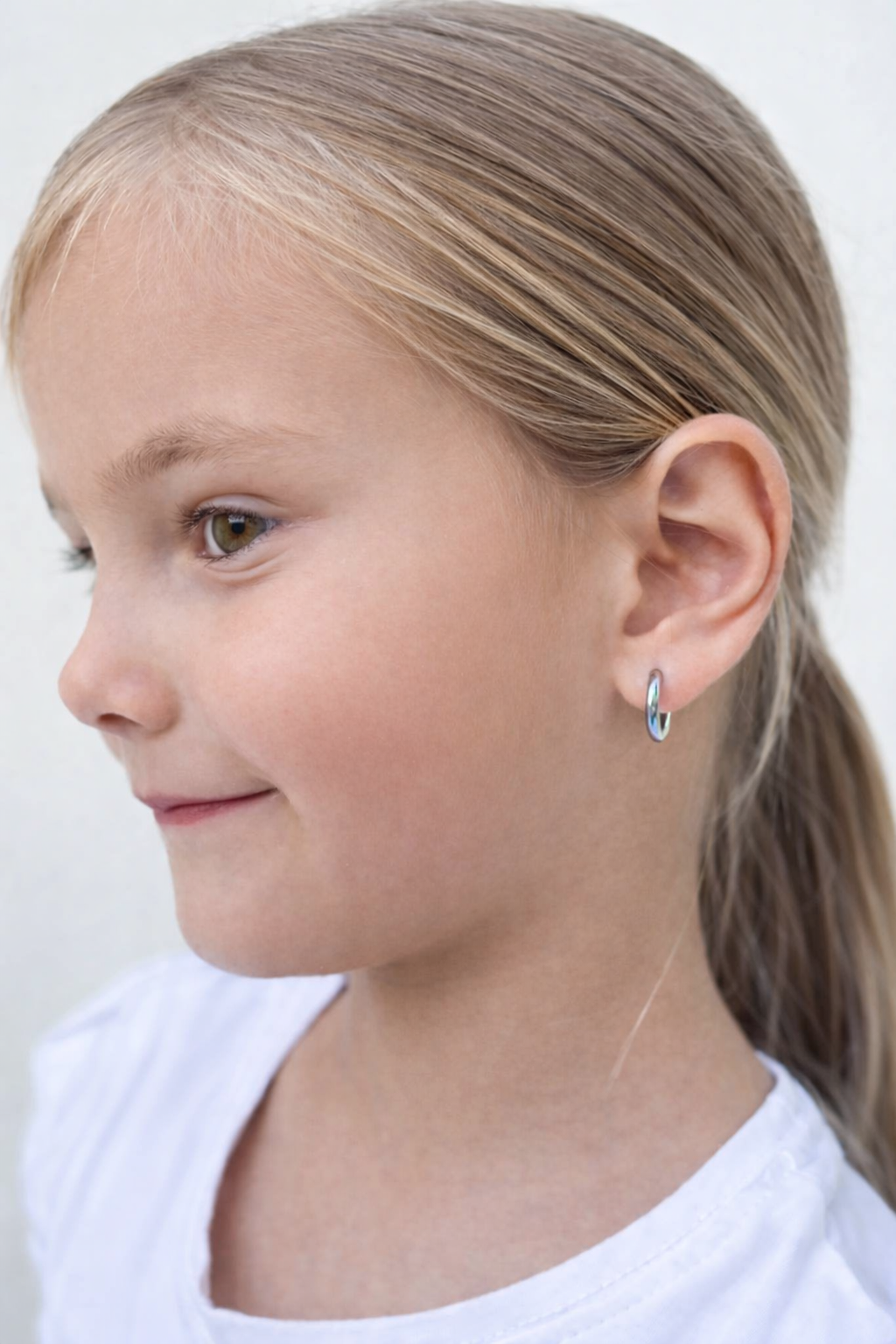 A young girl wearing 316L surgical steel hoop children's earrings, displaying a classic and timeless style.