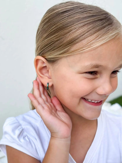 Smiling girl wearing children's earrings, showcasing anodised 316L surgical steel rainbow hoop earrings.