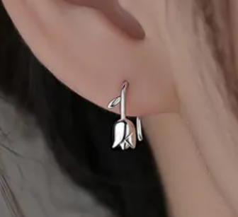 Close-up of children's earrings featuring sterling silver tulip reversible studs worn on a child's ear.