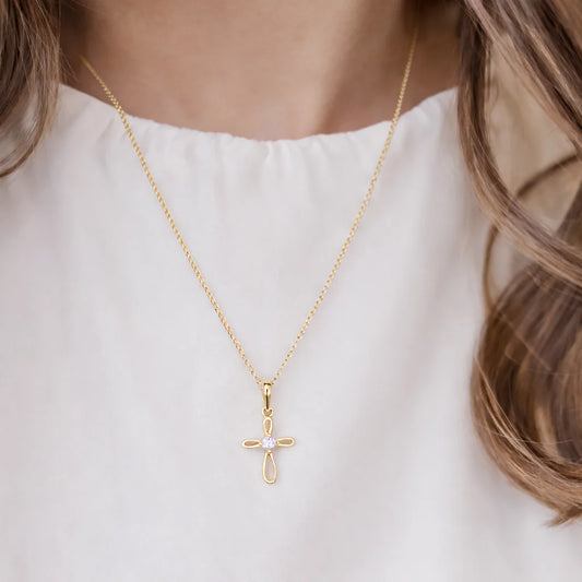 Gold necklace with a cross pendant worn by a girl on a white background
